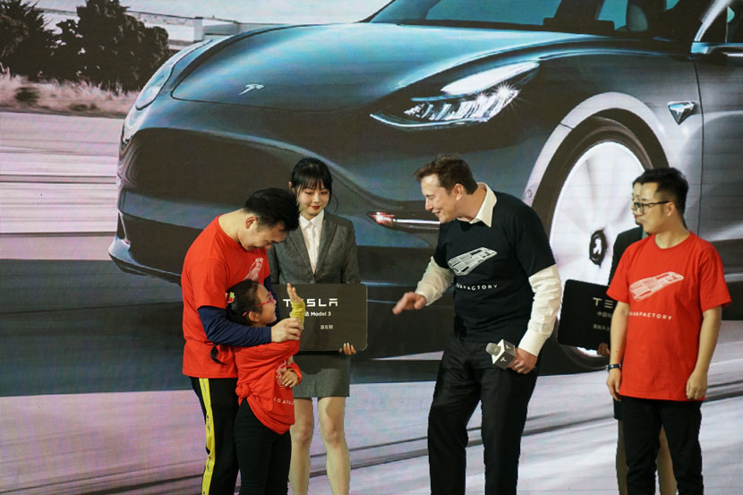Tesla CEO Elon Musk (center) greets customers during a delivery ceremony for the company’s China-made Model 3 sedans in Shanghai, Jan. 7, 2020. Bao Yumeng for Sixth Tone