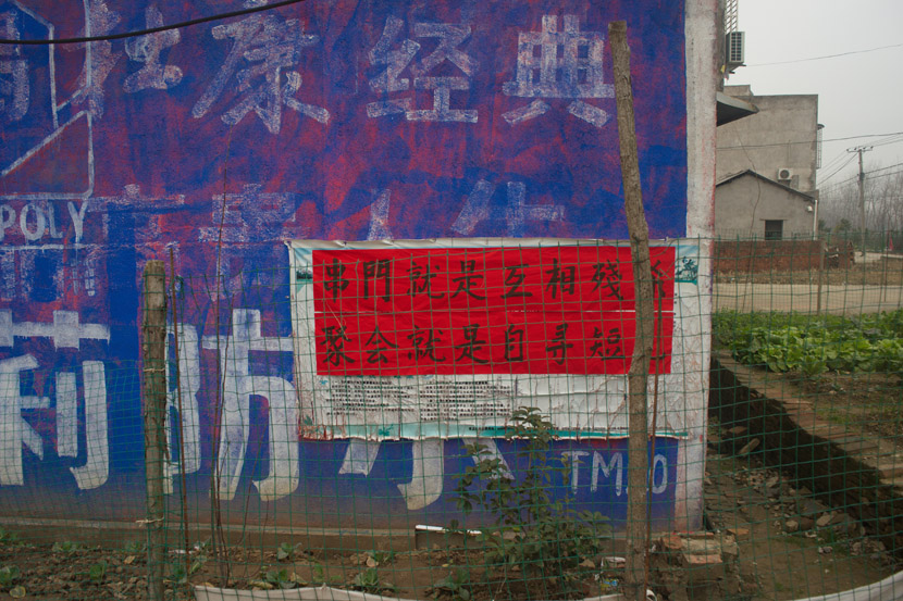A poster bearing the slogan, “Seeing Each Other Is Mutual Slaughter; Going to a Party Is to Seek Your Own End” is displayed in a village near Tianmen, Hubei province, Feb. 1, 2020. Yang Chenhui for Sixth Tone