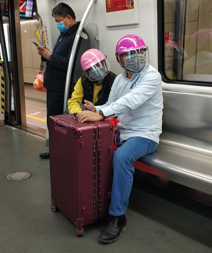 A couple wear helmets over their face masks on the subway in Guangzhou, Guangdong province, Jan. 29, 2020. Tan Qingju/Southern Metropolis Daily