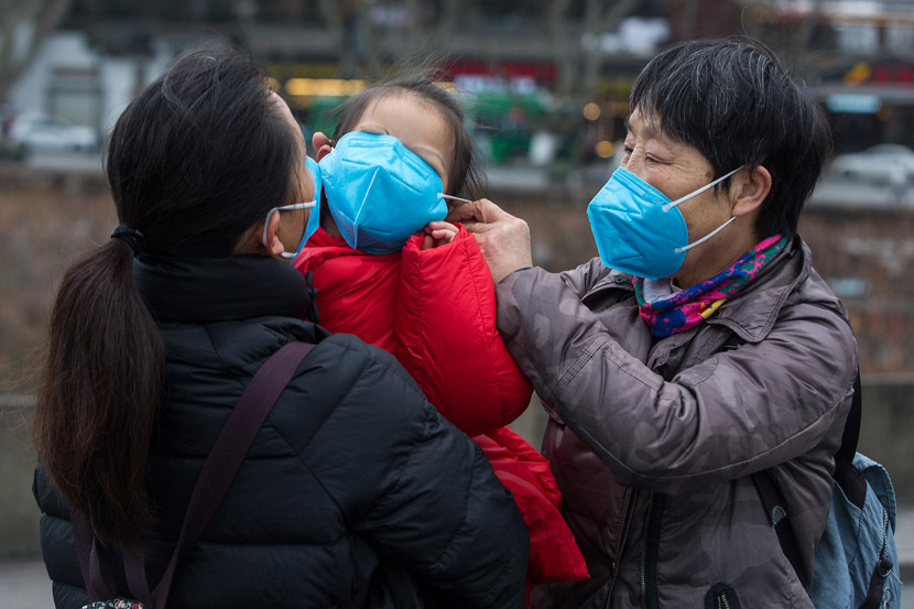 A woman forces her granddaughter to wear a face mask in Hangzhou, Zhejiang province, Jan. 28, 2020. Chen Zhongqiu for Sixth Tone