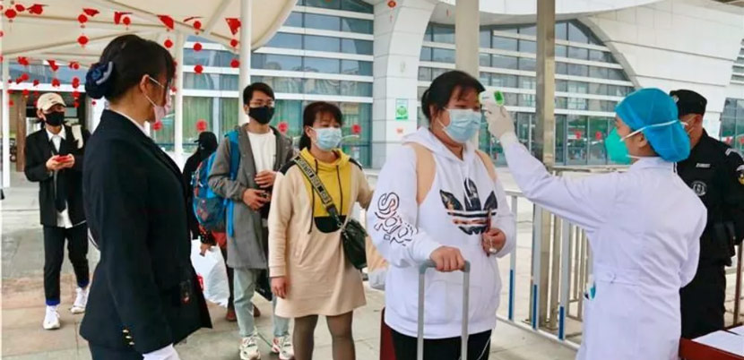 A medical worker takes the temperature of a passenger at a railway station in Fangchenggang, Guangxi Zhuang Autonomous Region, Jan. 24, 2020. Deng Wei/Fangchenggang Daily