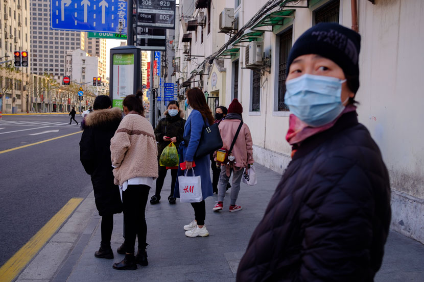People wait at a bus stop in Shanghai, Feb. 4, 2020. Wu Huiyuan/Sixth Tone