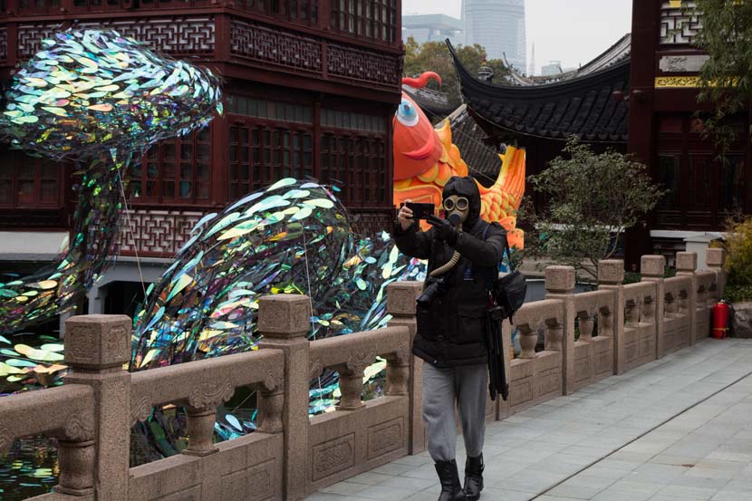 A man wearing a gas mask takes photos at Yu Garden during the Lantern Festival in Shanghai, Feb. 8, 2020. Shi Yangkun/Sixth Tone