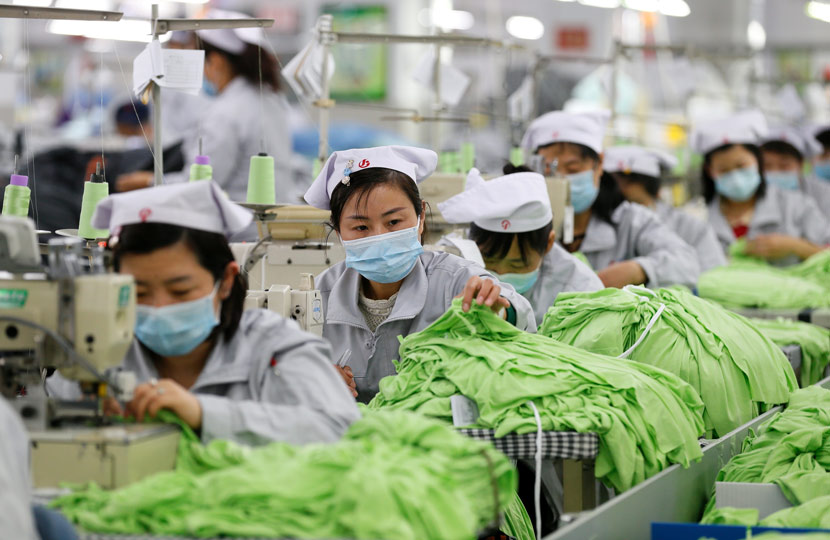 Workers wear face masks while sewing fabric at a reopened factory in Qingdao, Shandong province, Feb. 14, 2020. Liao Xiaopeng via Xinhua