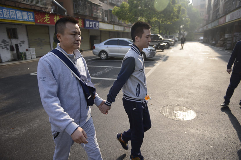 Sun Wenlin (right) holds his boyfriend’s hand as they walk to the People’s Court of Furong District for their lawsuit against the Bureau of Civil Affairs of Furong District, which rejected their marriage application in Changsha, Hunan province, April 13, 2016. IC