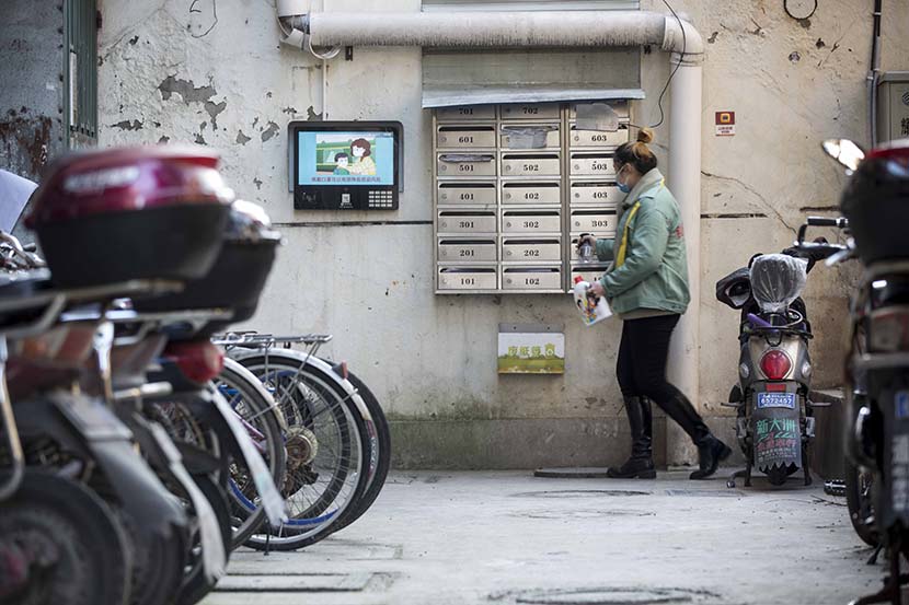 A community worker wipes down mailboxes with disinfectant in a residential area in Shanghai, Jan. 1, 2020. Yi Chuan for Sixth Tone