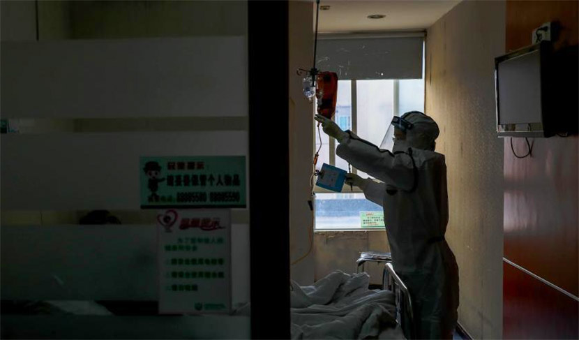 A medical worker checks on a patient at a hospital in Wuhan, Hubei province, Feb. 3, 2020. Zhang Chang/CNS