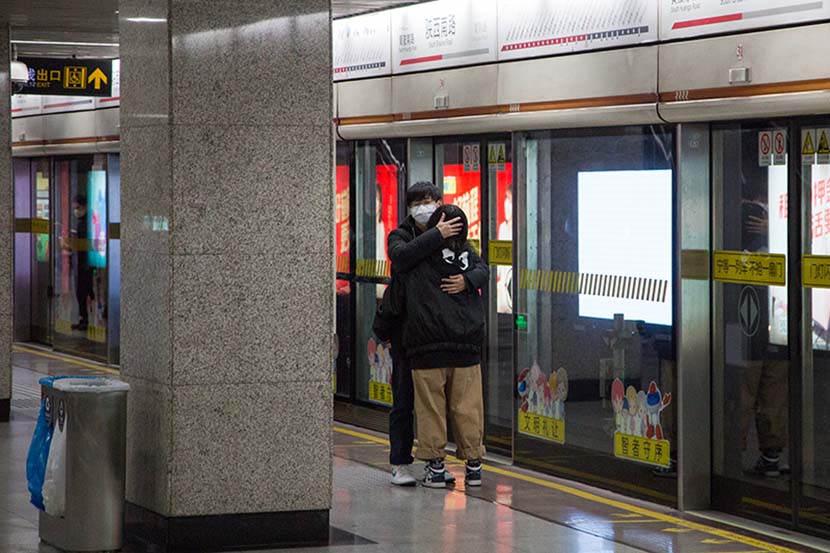 A young couple embrace on the subway platform at South Shaanxi Road Station in Shanghai, Feb. 6, 2020. Shi Yangkun/Sixth Tone