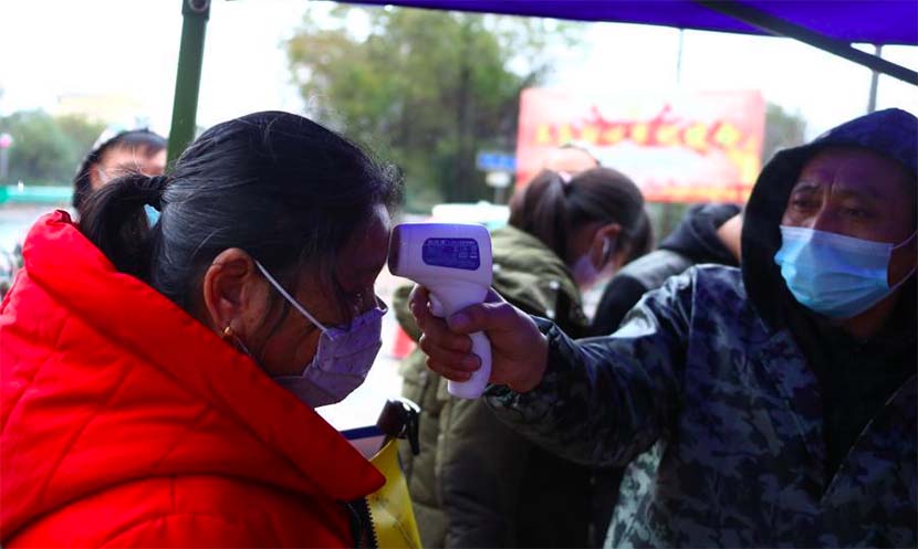 A medical worker takes a woman’s temperature in a village near Nanchang, Jiangxi province, Jan. 26, 2020. Liu Zhankun/CNS