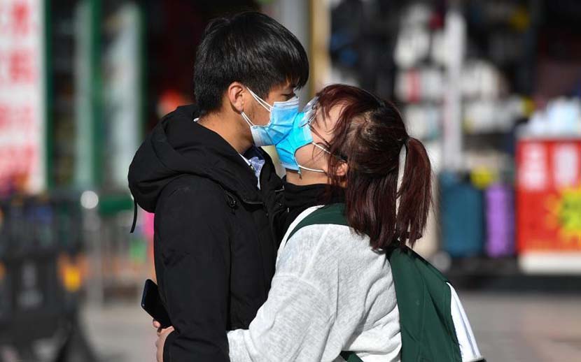 A couple wearing face masks kiss at a railway station in Kunming, Yunnan province, Feb. 17, 2020. Liu Ranyang/CNS