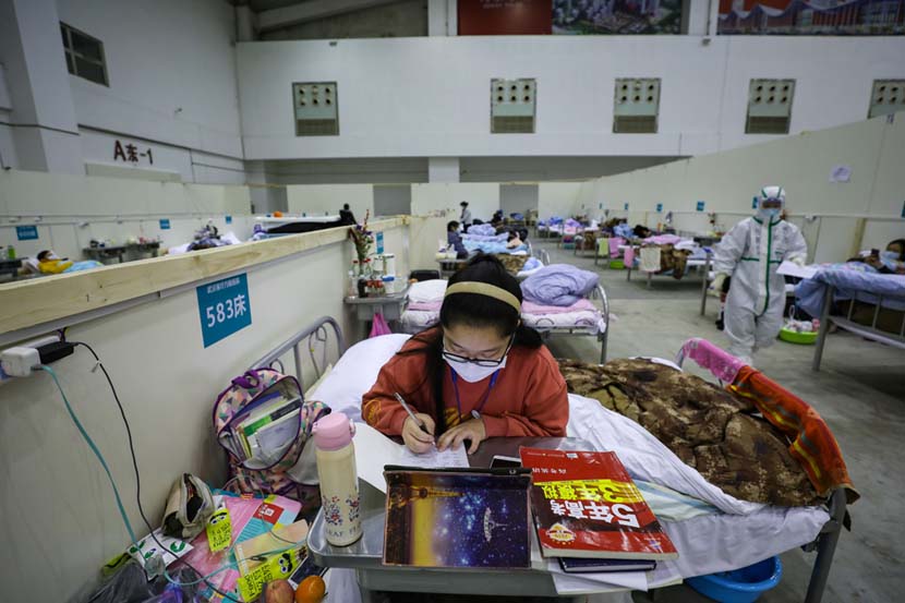A teenage coronavirus patient studies for the college entrance exams at a temporary “shelter hospital” in Wuhan, Hubei province, Feb. 18, 2020. Yuan Zheng/Changjiang Daily