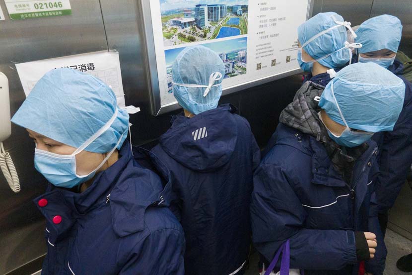 Medical workers stand with their backs to one other to avoid the risk of cross-infection as they take an elevator at the Optics Valley Branch of Tongji Hospital in Wuhan, Hubei province, Feb. 20, 2020. Xinhua
