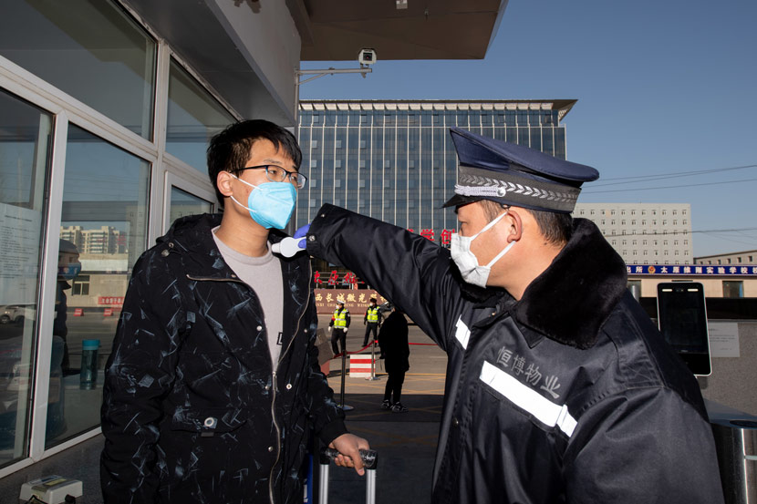 A guard tests an employee’s temperature at the entrance of a factory in Taiyuan, Shanxi province, Feb 22, 2020. Hu Yuguang/IC