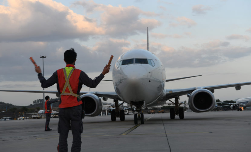 A ground control worker directs a commercial jet at an airport in Sanya, Hainan province, Feb. 24, 2020. Sha Xiaofeng/IC