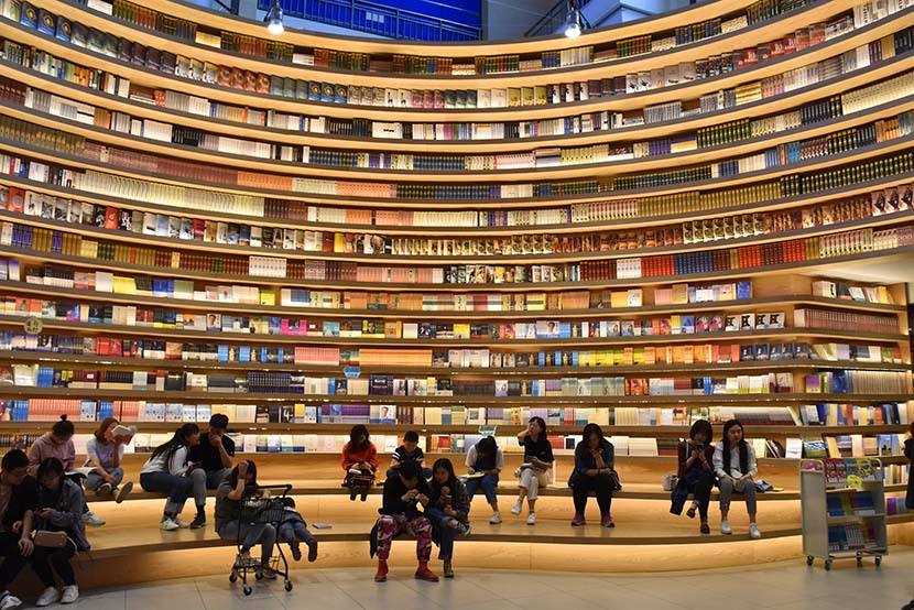 People browse for books at a new store with wraparound shelving units in Hohhot, Inner Mongolia Autonomous Region, April 21, 2019. IC