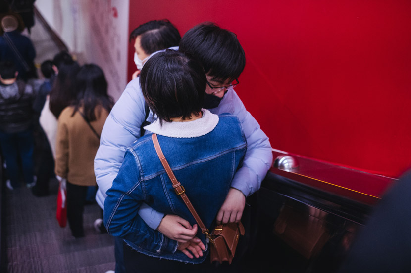 A couple embraces on an escalator in Shanghai, Feb. 27, 2020. Wu Huiyuan/Sixth Tone