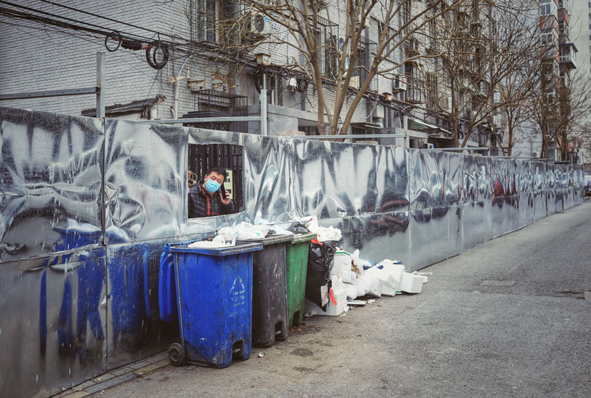 A man makes a call near a temporary trash dump in Beijing, Feb. 24, 2020. Many communities have closed themselves off as the city battles to keep the COVID-19 epidemic from spreading. Pu Feng/dixphoto