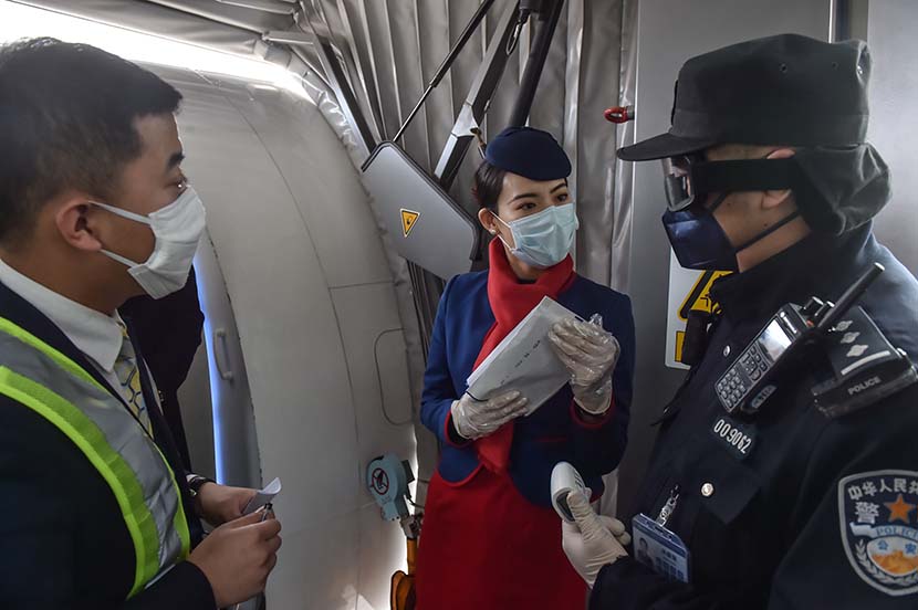 Police officers ask a cabin crew member for foreign passengers' personal information at Beijing Daxing International Airport, Feb. 1, 2020. Xinhua