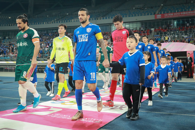 Players from clubs in Guangdong and Hebei provinces walk onto the field before a China League One match in Shijiazhuang, Hebei province, Sept. 22, 2019. IC