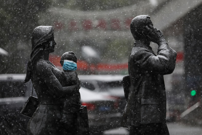 A mask has been placed over a child statue’s face on a snowy day in Wuhan, Hubei province, Feb. 15, 2020. Yuan Zheng for Sixth Tone