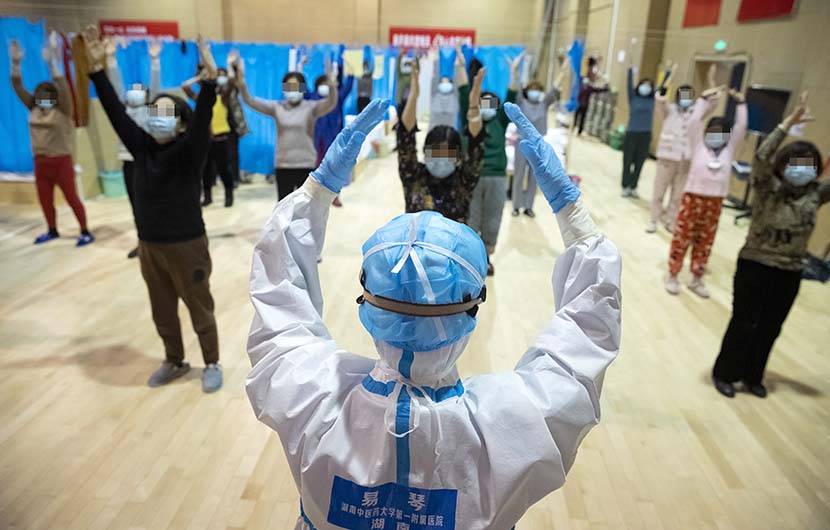 A medical worker leads an exercise session for COVID-19 patients with mild symptoms at a temporary “shelter hospital” in Wuhan, Hubei province, Feb. 25, 2020. Shen Bohan/Xinhua