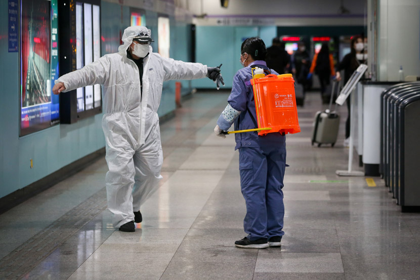 A cleaner disinfects a subway worker in Shanghai, Feb. 14, 2020. Zhu Weihui for Sixth Tone