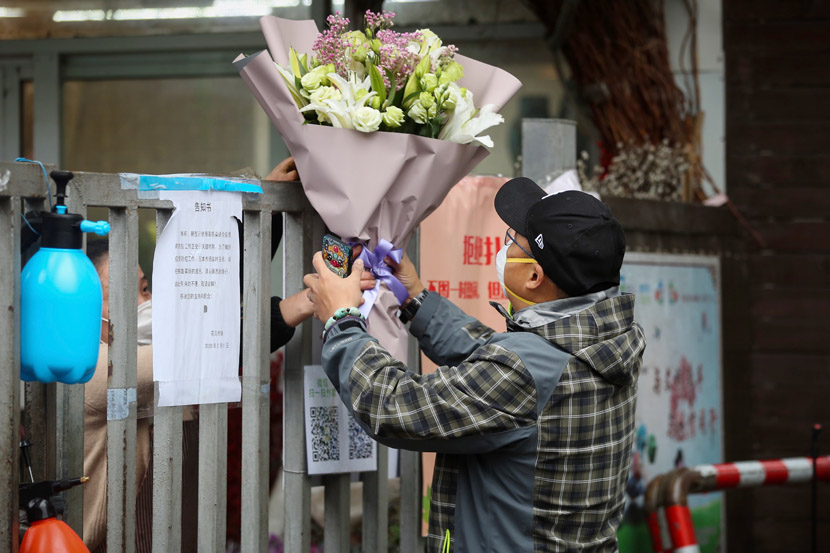 On Valentine’s Day, a florist delivers a bouquet of flowers over the locked gate of a residential community in Shanghai, Feb. 14, 2020. Zhu Weihui for Sixth Tone