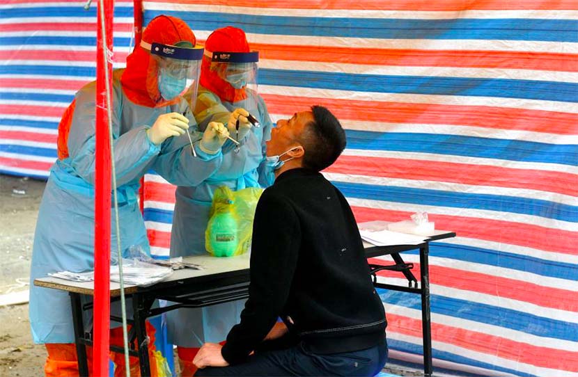 Two medical workers collect throat swabs from a returning migrant worker in Fuzhou, Fujian province, March 5, 2020. CNS