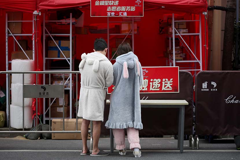 A couple in pajamas at their residential community’s delivery pickup station in Shanghai, March 4, 2020. Zhu Weihui for Sixth Tone