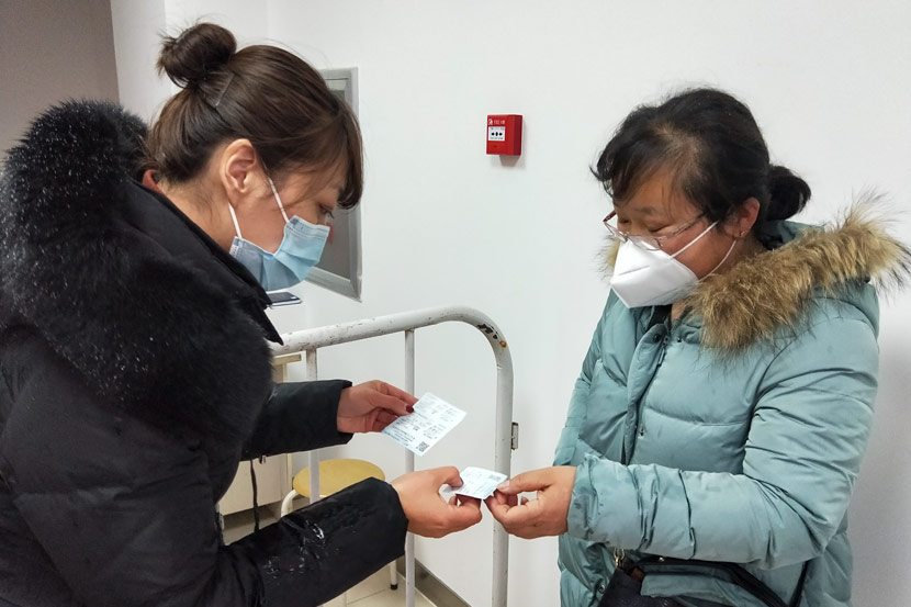Liu Xuqing (left) checks a resident’s tickets after she arrived in the community, in Shenyang, Liaoning province, February 2020. Courtesy of Liu Xuqing