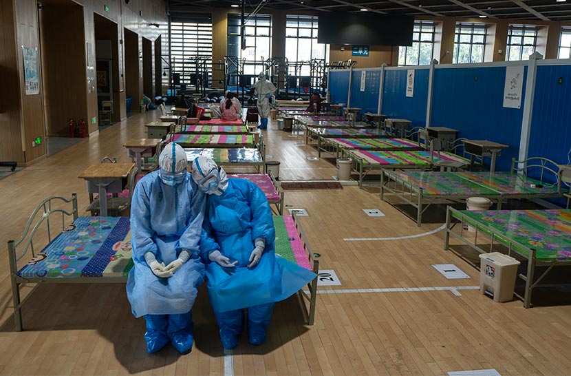 Two medical workers dispatched from Qinghai province to aid with COVID-19 treatment and containment efforts rest at a closed-down “shelter hospital” in Wuhan, Hubei province, March 12, 2020. Xiao Yijiu/Xinhua
