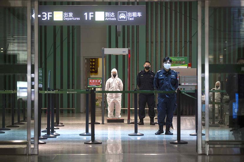 Medical workers and police officers wait for arriving passengers at Shanghai Hongqiao International Airport, March 18, 2020. Ying Yi for Sixth Tone