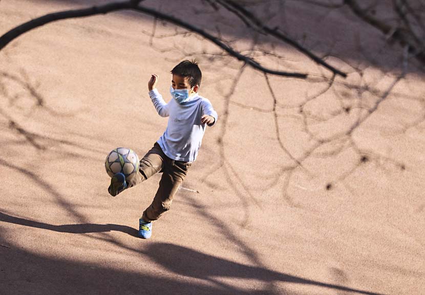 A boy plays soccer in a Beijing neighborhood, March 17, 2020. Xinhua