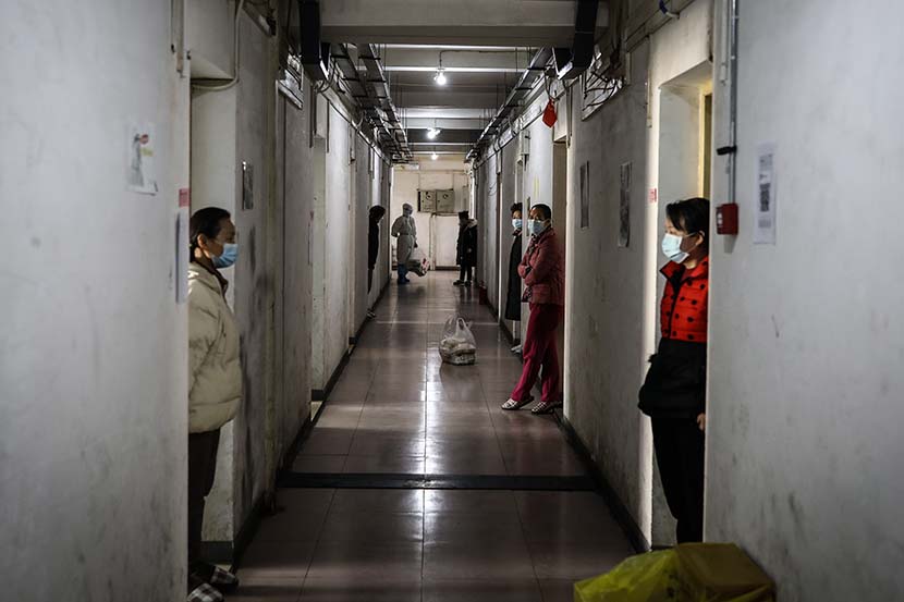 Men rest along the gallery outside their rooms at the quarantine center set up in the dormitories of Wuhan Vocational College of Software and Engineering in Wuhan, Hubei province, March 13, 2020. Zhao Di/China Youth Daily