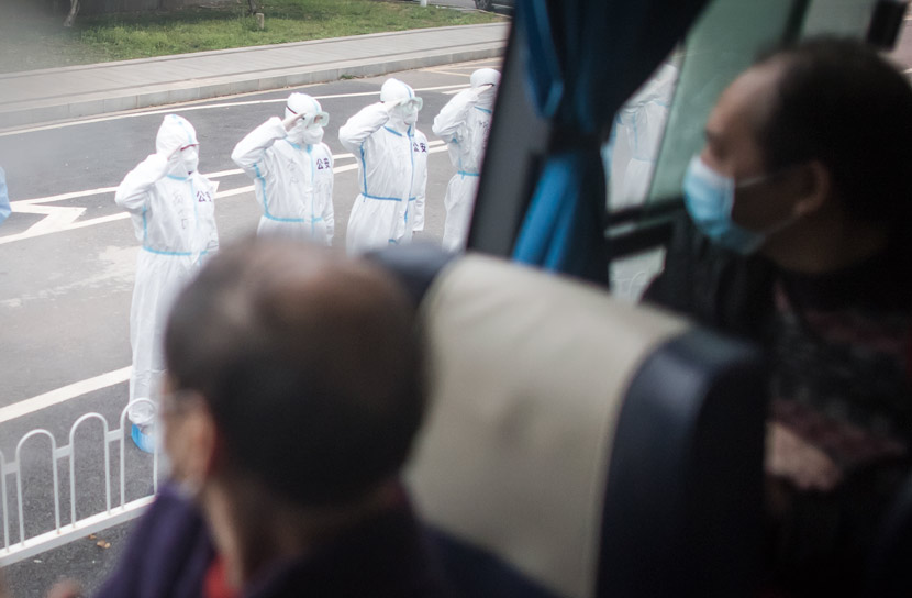 Policemen in protective gear salute recovered patients at the end of their quarantine periods in Wuhan, Hubei province, March 12, 2020. Xiao Yijiu/Xinhua