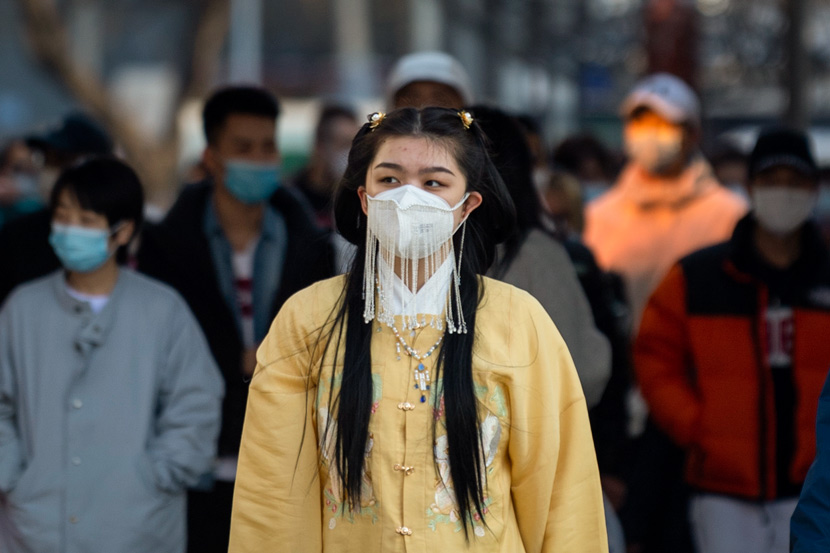 A young woman wearing a traditional “hanfu” outfit sports a fashion-forward face mask in Beijing, March 28, 2020. IC