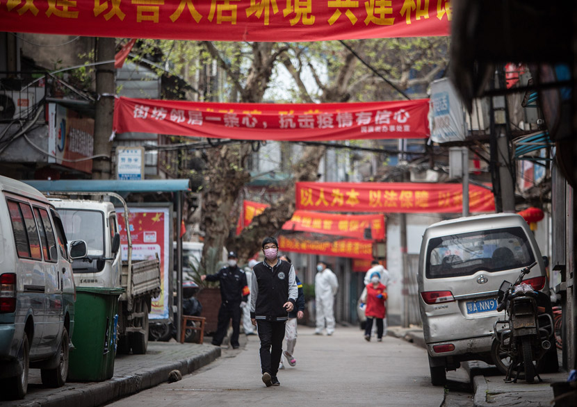 A young man walks past banners bearing propaganda slogans in a residential community in Wuhan, Hubei province, March 24, 2020. Li Zhengni/China Youth Daily