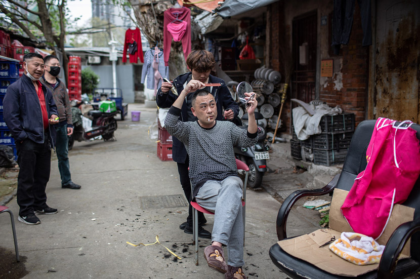 A local resident gives a neighbor a haircut in Wuhan, Hubei province, March 24, 2020. Li Zhengni/China Youth Daily
