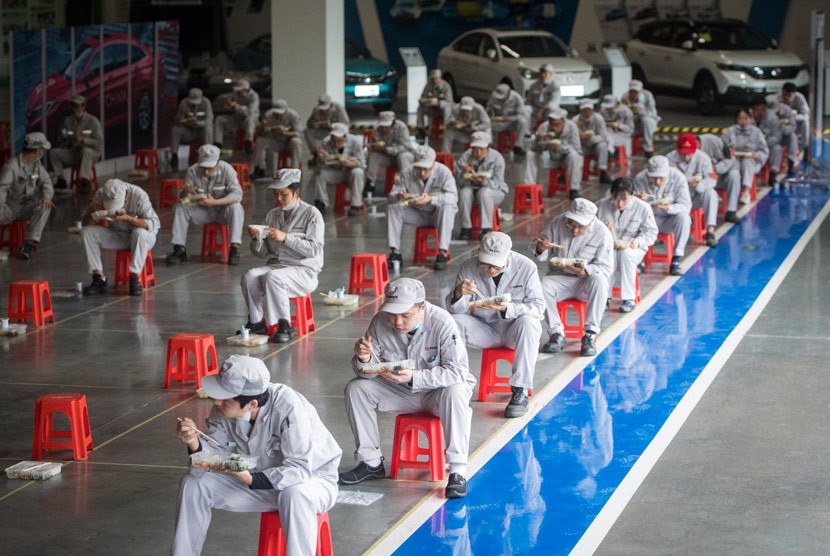 Workers observe social distancing rules while having lunch at a workshop in Wuhan, Hubei province, March 24, 2020. Xiao Yijiu/Xinhua