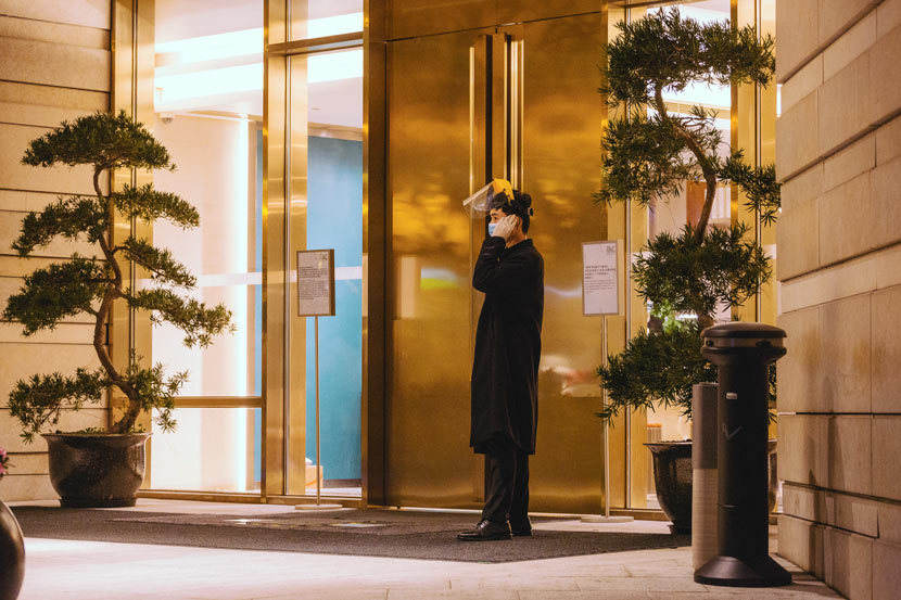 A waiter at the entrance of a hotel in Shanghai, Feb. 27, 2020. Wu Huiyuan/Sixth Tone