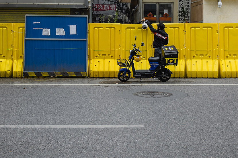 A delivery driver passes food over a barrier in Wuhan, Hubei province, March 22, 2020. Gerry Yin/Wild Photos