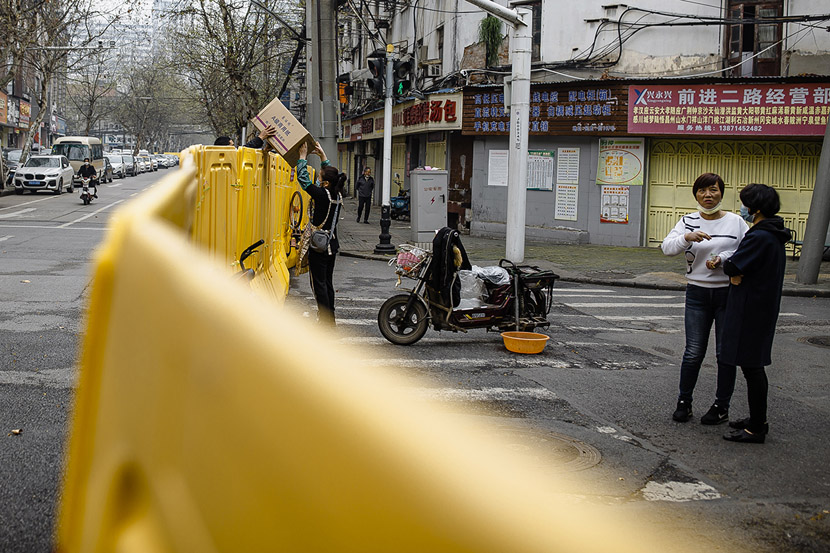 A delivery driver passes a package to a resident in Wuhan, Hubei province, March 22, 2020. Gerry Yin/Wild Photos