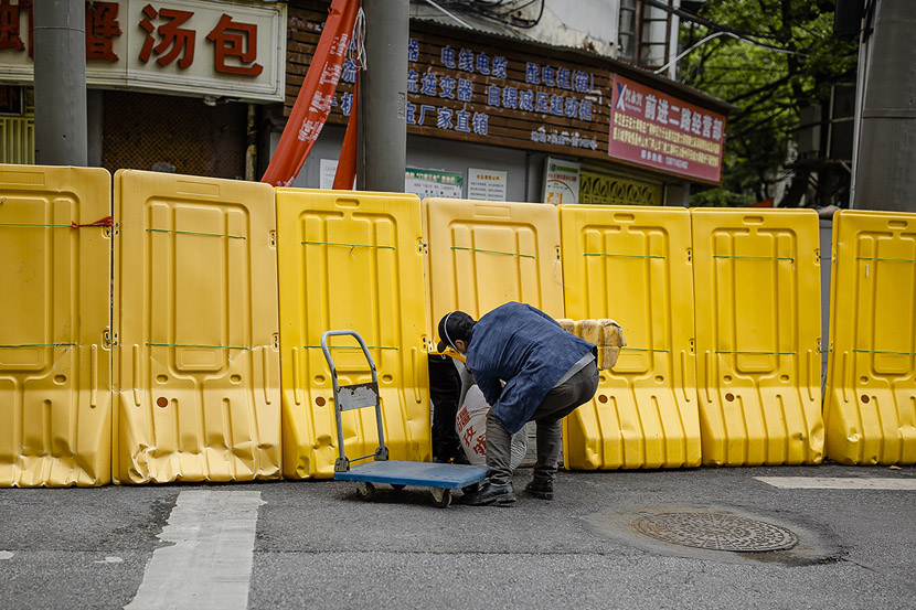 A man passes a heavy shipment through a hole in the wall’s base in Wuhan, Hubei province, April 1, 2020. As time went on and the threat receded, residents began to find creative ways to break through their confinement. Gerry Yin/Wild Photos