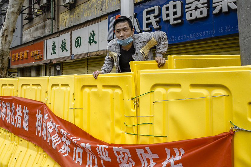 A resident vaults over a barrier to buy soy sauce in Wuhan, Hubei province, March 22, 2020. Gerry Yin/Wild Photos