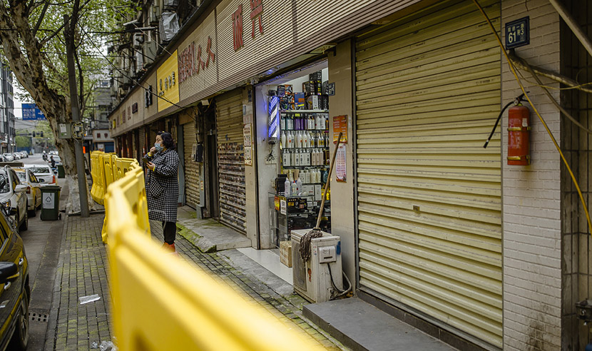 A salon owner eats sunflower seeds while looking out at the street in Wuhan, Hubei province, April 1, 2020. She says she has had no customers recently, but is keeping her store open as a way to get some air. Gerry Yin/Wild Photos