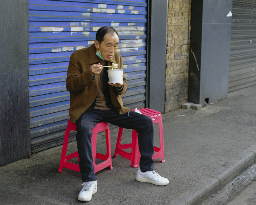 A man eats breakfast on the sidewalk in Wuhan, Hubei province, April 8, 2020. Shi Yangkun/Sixth Tone