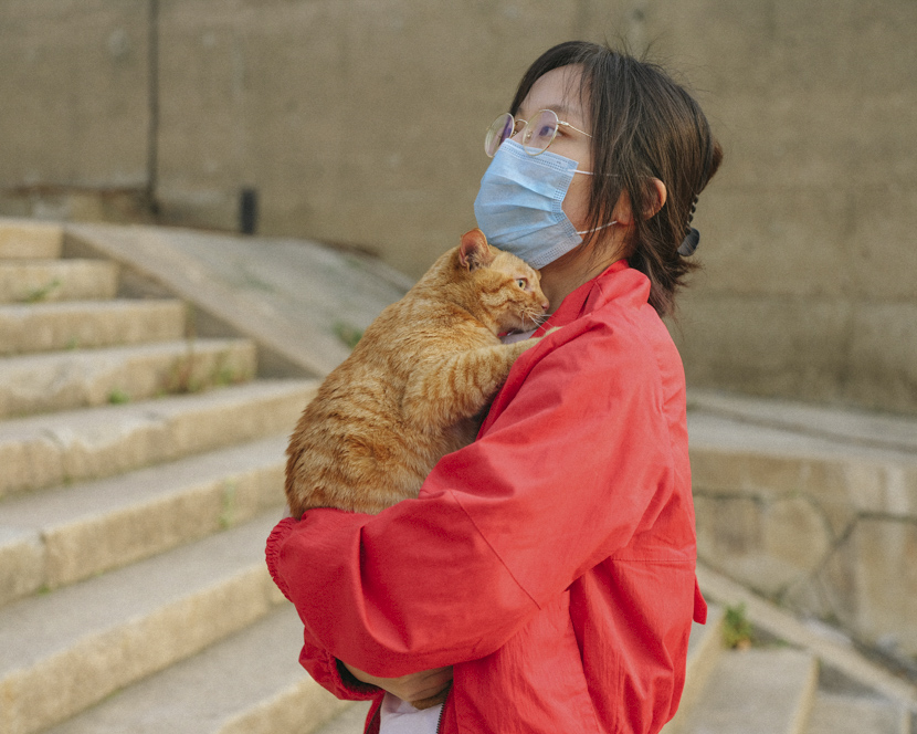 A woman holds her cat by the Yangtze River in Wuhan, Hubei province, April 7, 2020. Shi Yangkun/Sixth Tone