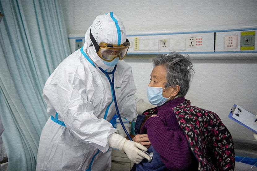 A member of the Guangdong medical support team checks on a patient at an ICU in Hankou Hospital in Wuhan, Hubei province, March 3, 2020. Southern Visual/People Visual