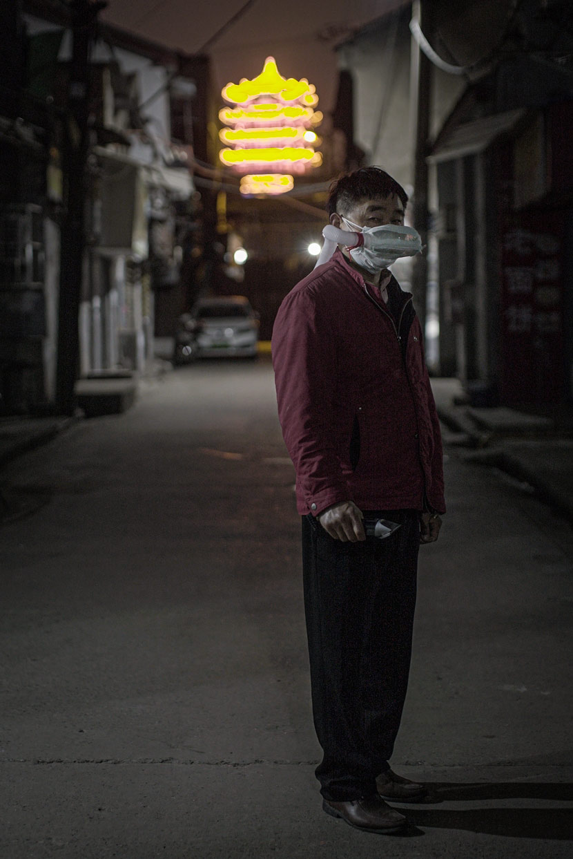 A barber wearing a handmade mask poses for a photo in Wuhan, Hubei province, April 8, 2020. In the background is the Yellow Crane Tower, one of the landmarks of Wuhan. Yang Shenlai for Sixth Tone