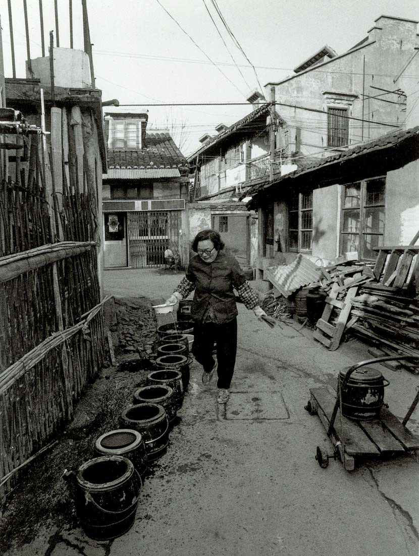 A woman washes chamber pots on Renji Road, Shanghai, 1997. Courtesy of Wu Jianping